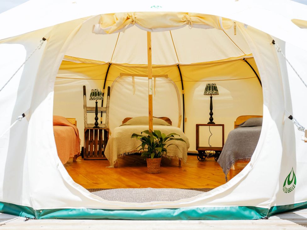 A bedroom setup inside a tent with beds and lamps at 