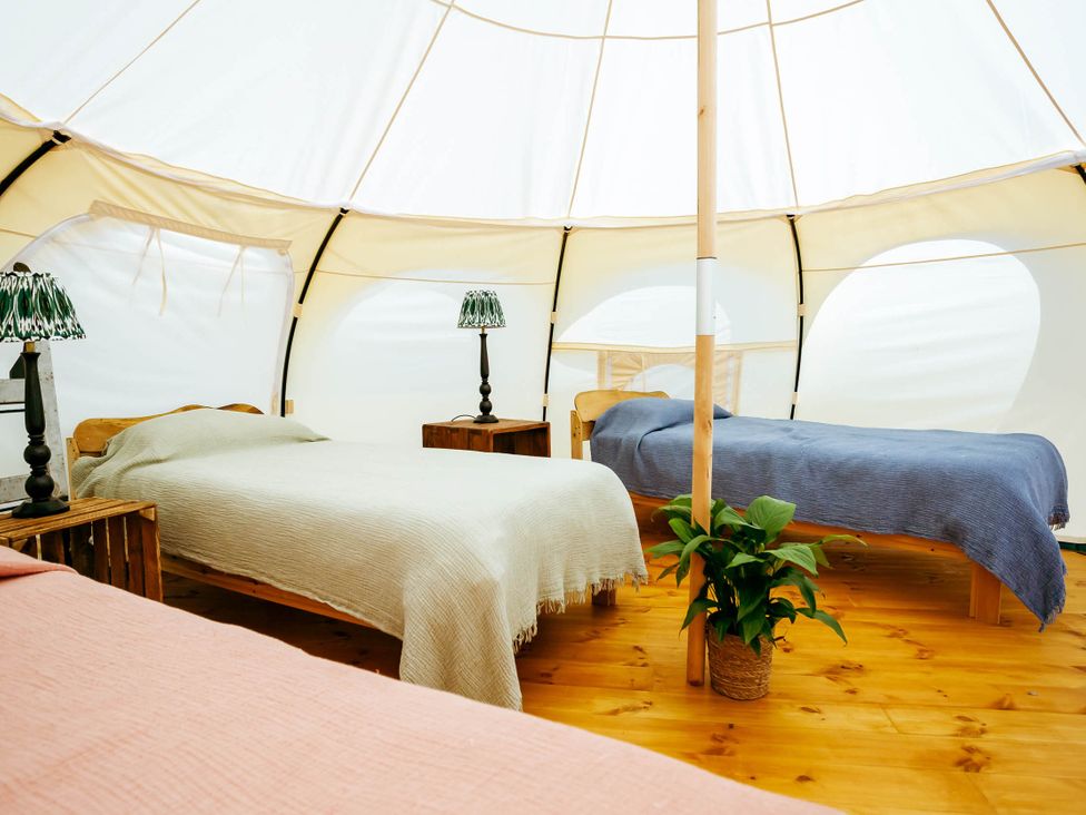 A tent interior with beds and lamps at 