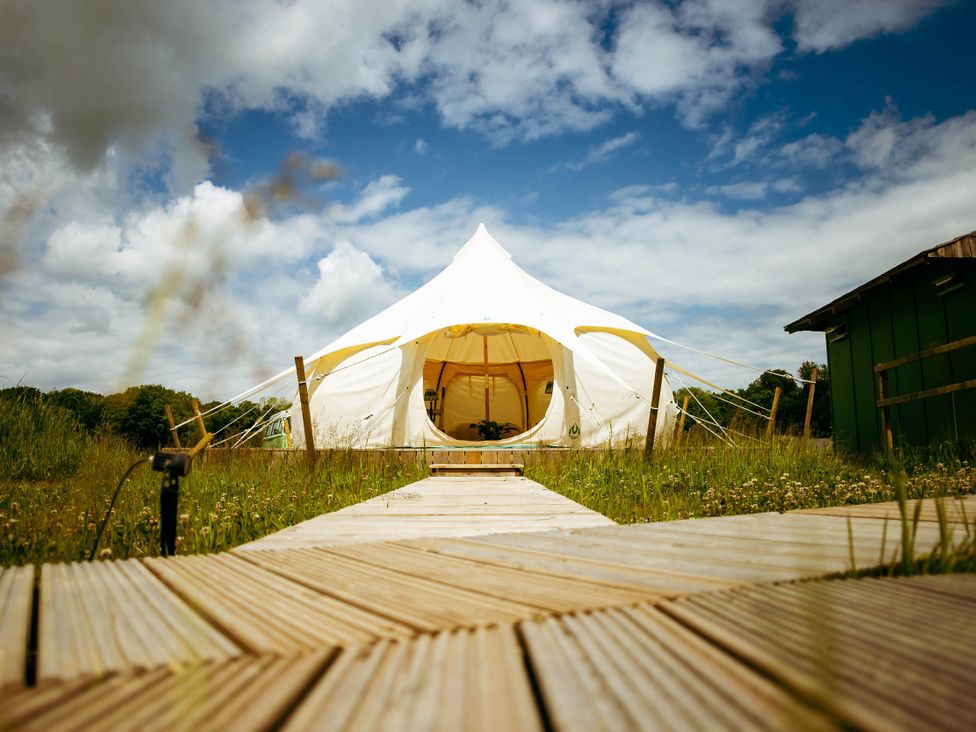 A tent on a pathway in a grassy area near a building