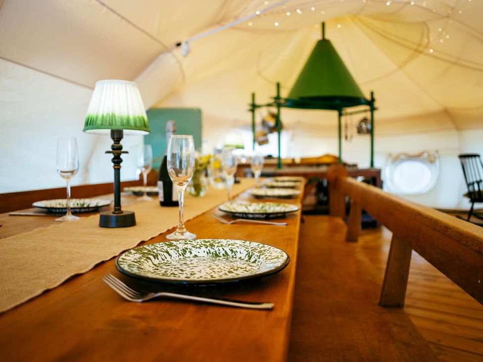 A dining room with a long table set for a meal in a tent at 