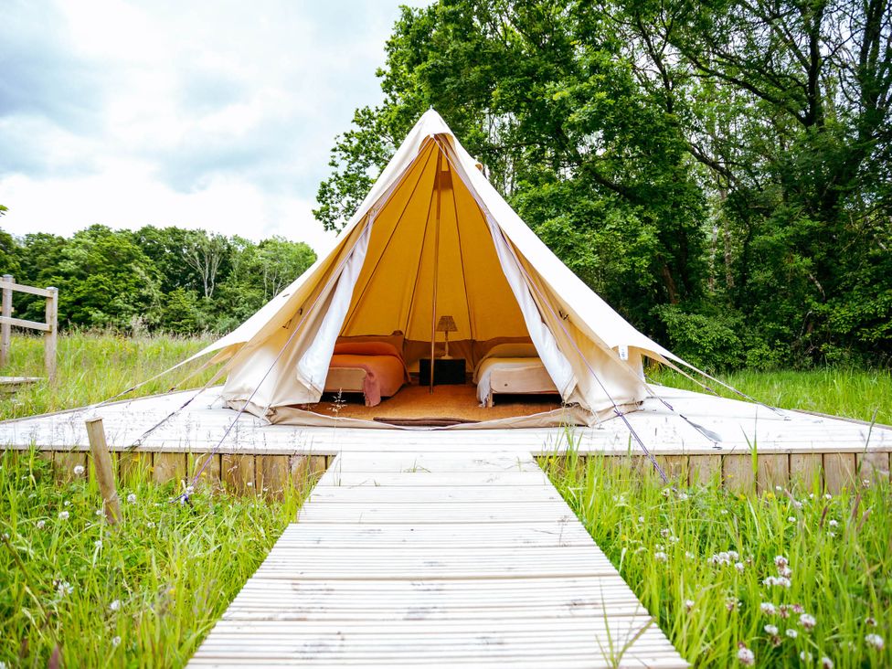 A tent with beds inside on a wooden deck in a field