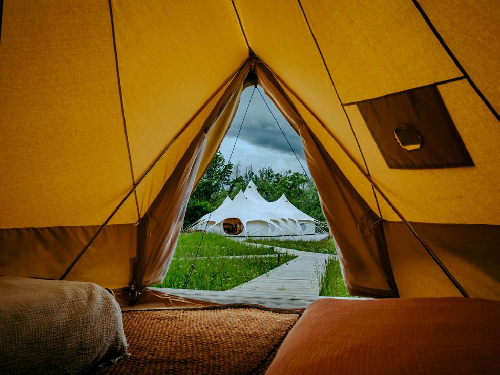 View from inside a tent featuring an outdoor path and white tents