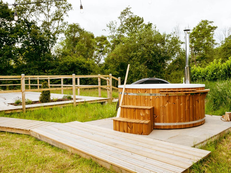 A hot tub with wooden deck and fence in a garden at 