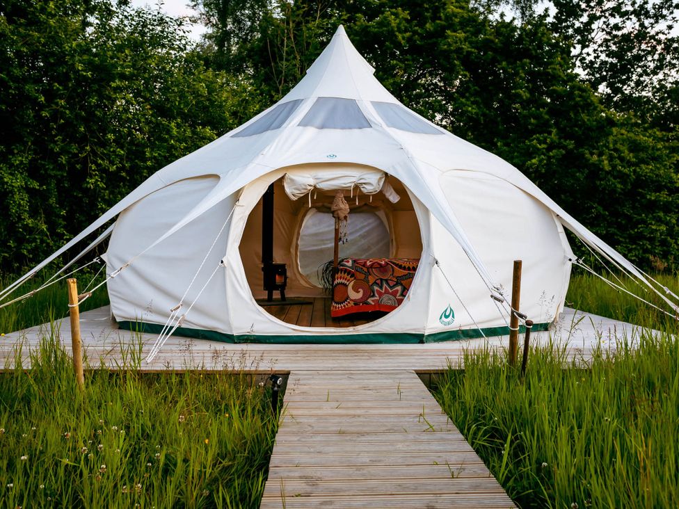 A yurt with a wooden walkway surrounded by grass
