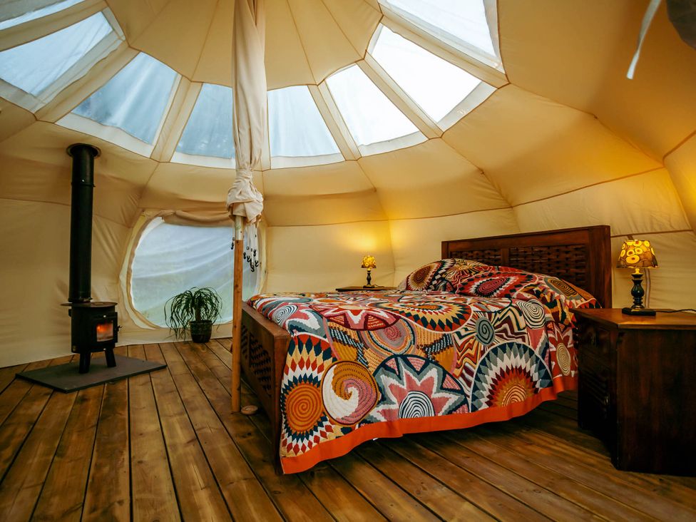 A bedroom with a bed and wood stove in a glamping tent