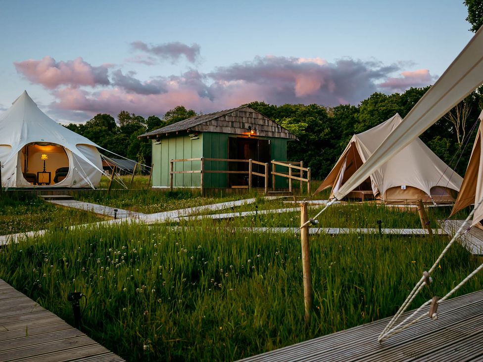 Glamping tents and a wooden cabin in an outdoor area at 