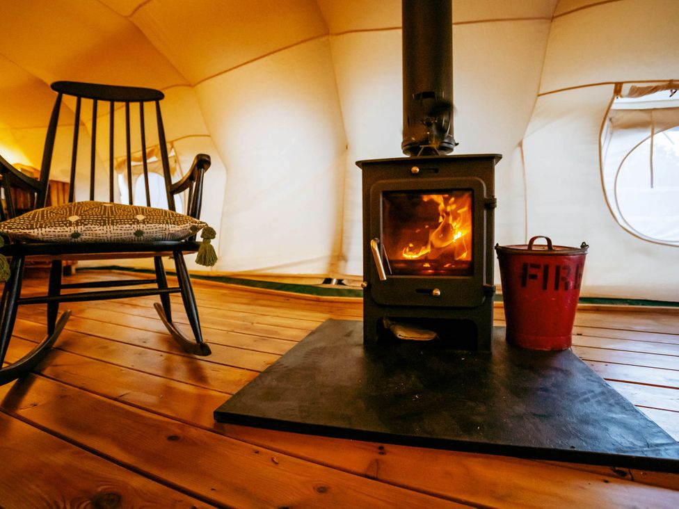 A living room with a wood stove and rocking chair at the property in the tent