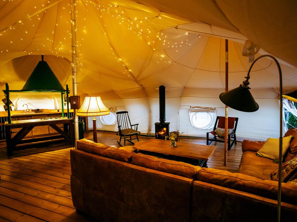 A living room with a sofa and kitchen area in a tent