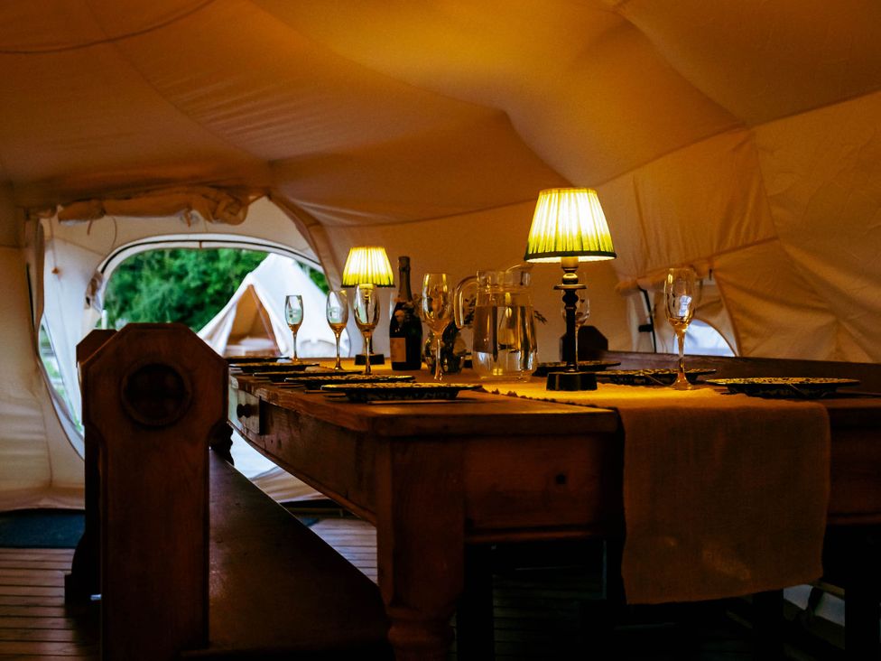 A dining room with a table set at a glamping site in a tent