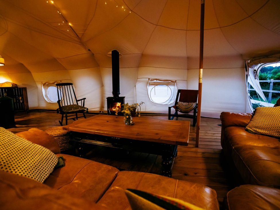 A living room with a wooden coffee table and a wood stove in a glamping tent at 