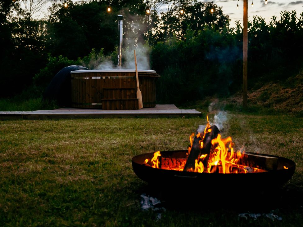 A fire pit with flames and a hot tub at an outdoor setting