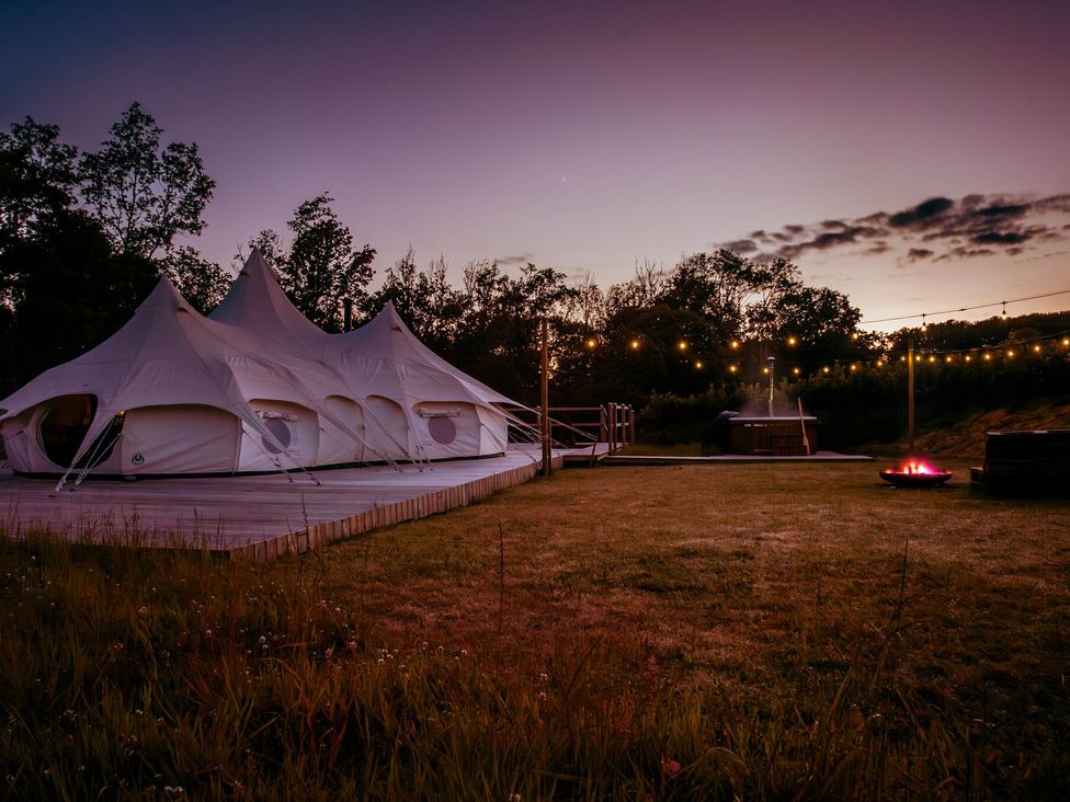 A glamping tent with a fire pit and hot tub at a property