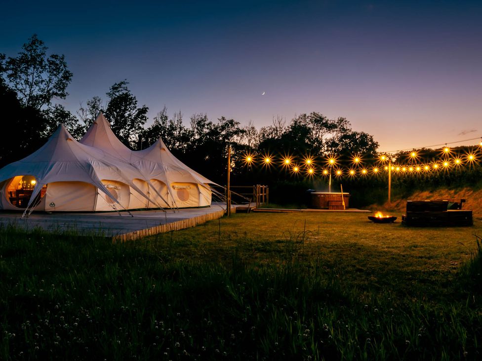 A tent with string lights and a fire pit at an outdoor space
