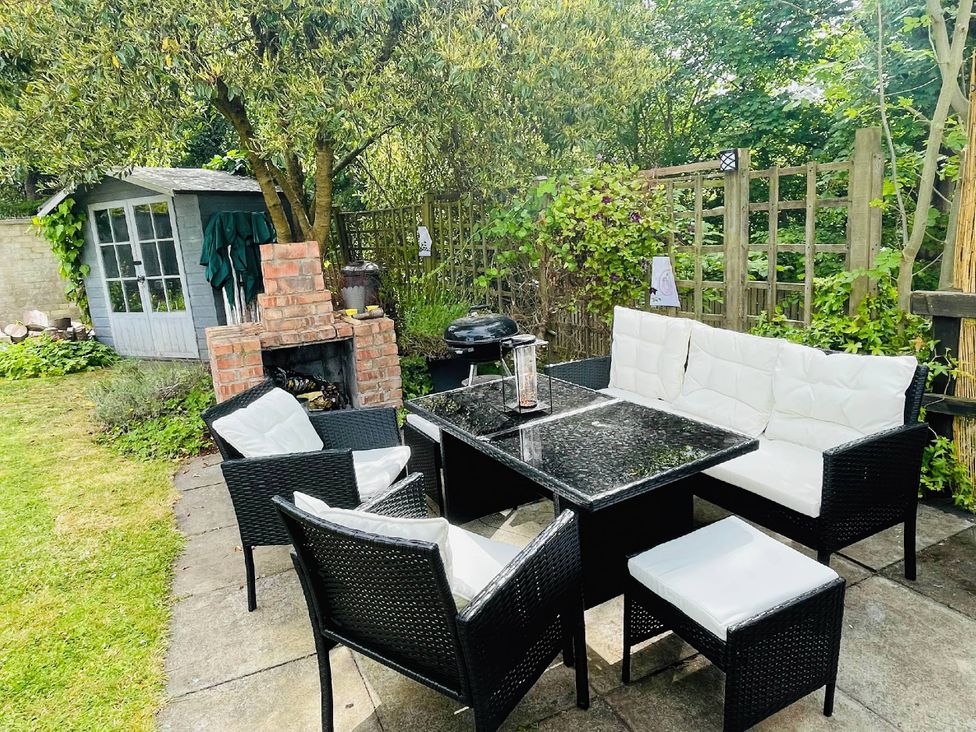 A patio set with chairs and table in a garden with a shed at the property
