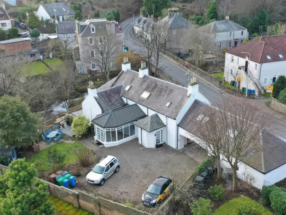 A house with a driveway and parked cars in a garden area