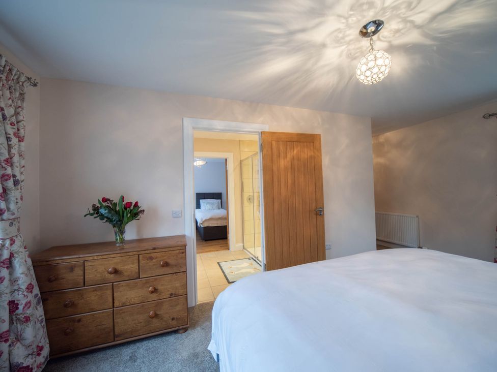 A bedroom with a bed, dresser, and door leading to a bathroom at The Old Barn in Manchester