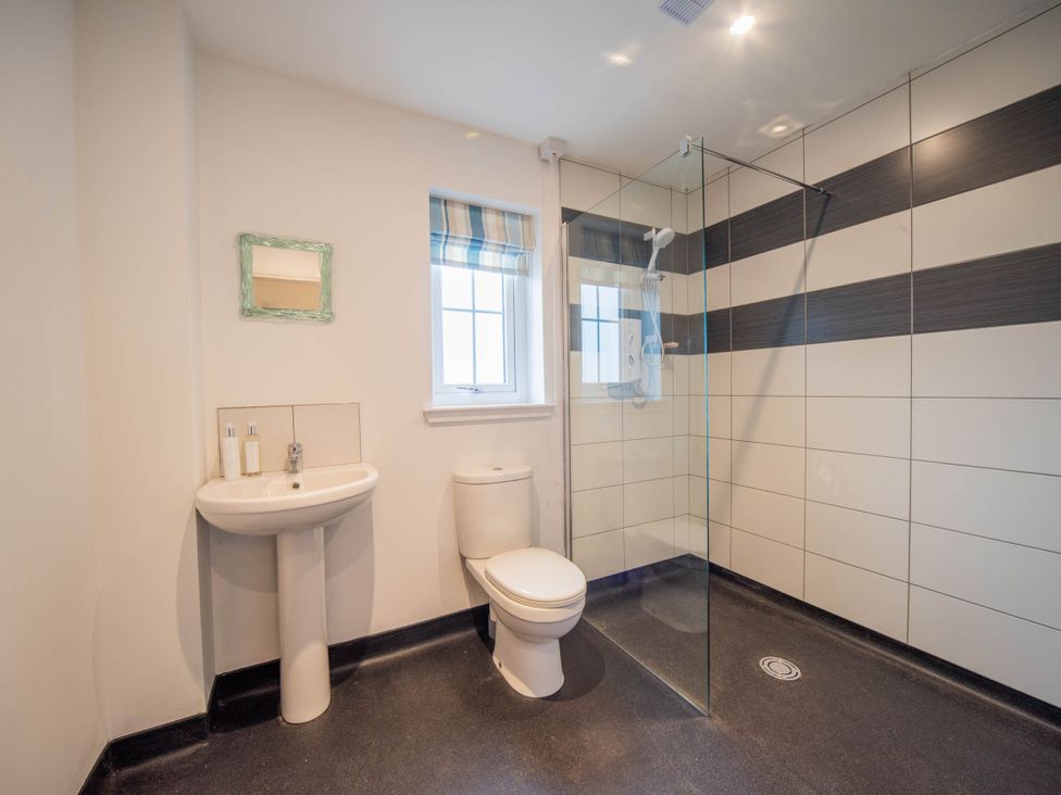 A bathroom with a shower, toilet, and washbasin at 