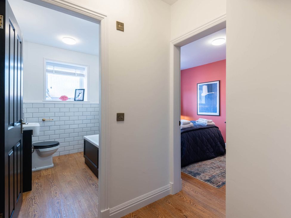 A bathroom with a toilet and sink and a bedroom with towels and art at the property in location