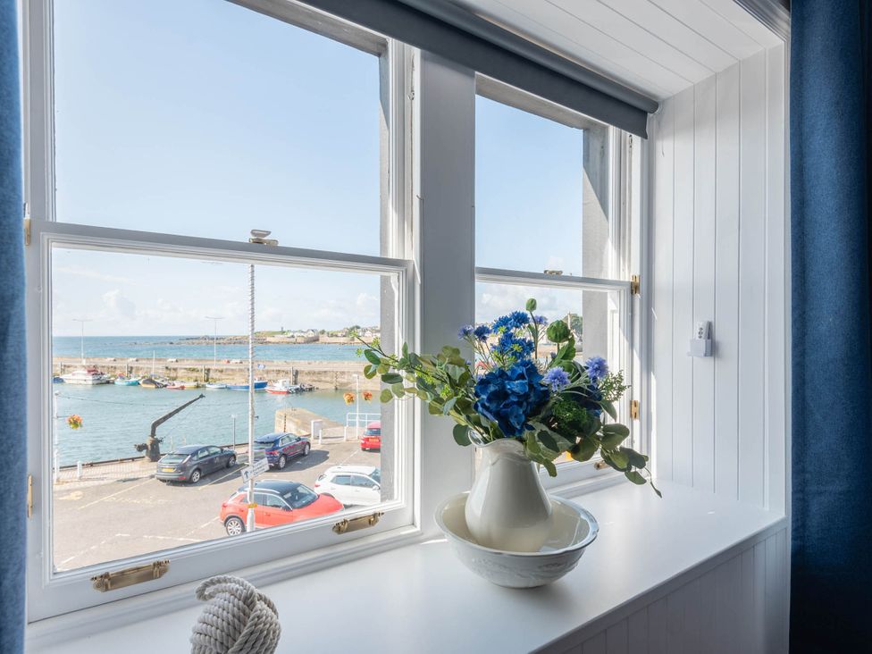 A window with a vase of flowers and a bowl at a property