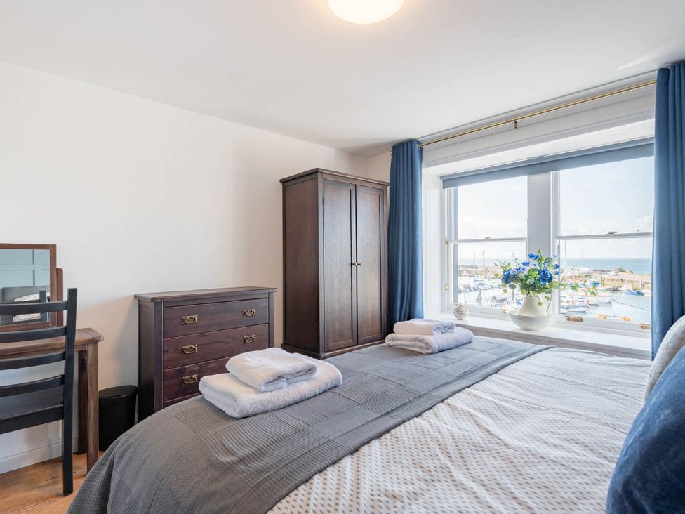 A bedroom with a bed and dresser overlooking a marina at the property in 