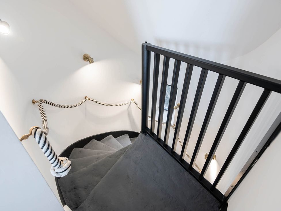 A staircase with a black handrail and light fixtures at the staircase