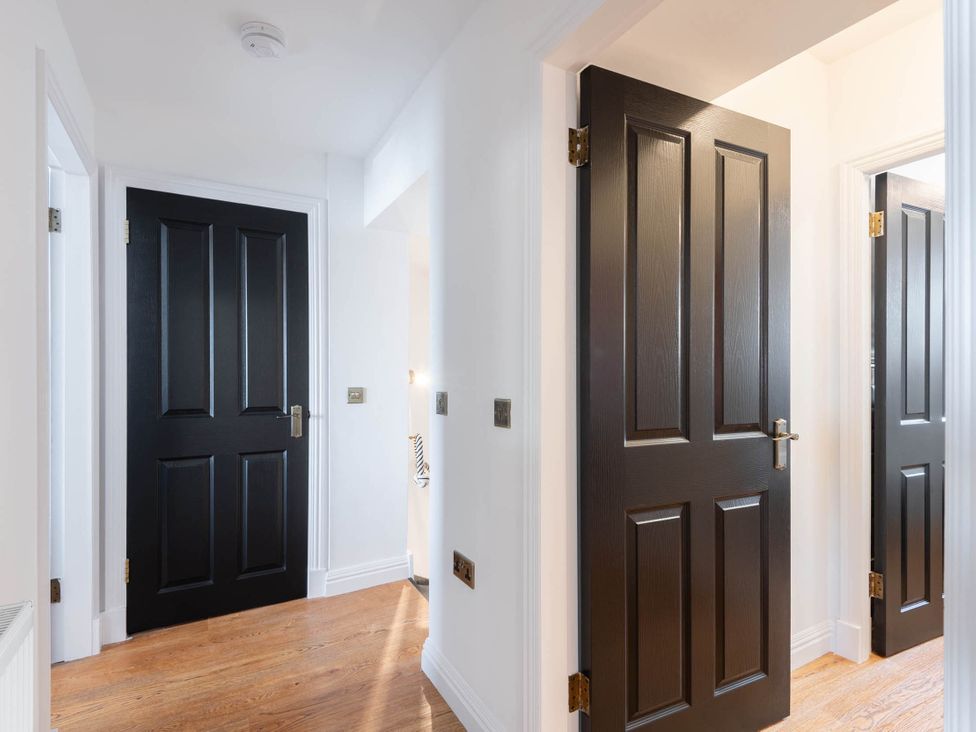A hallway with black doors and wooden flooring at The Old Barn in Manchester