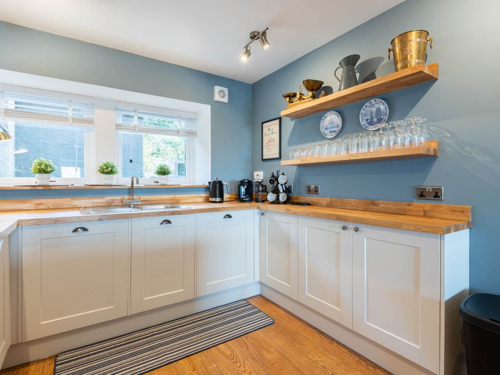 A kitchen with a sink and shelves holding glasses at a property in an unspecified location