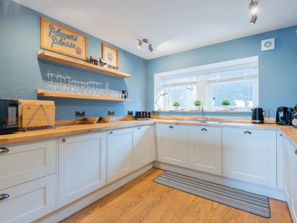 A kitchen with shelves, glasses, and appliances at The Old Barn in Manchester