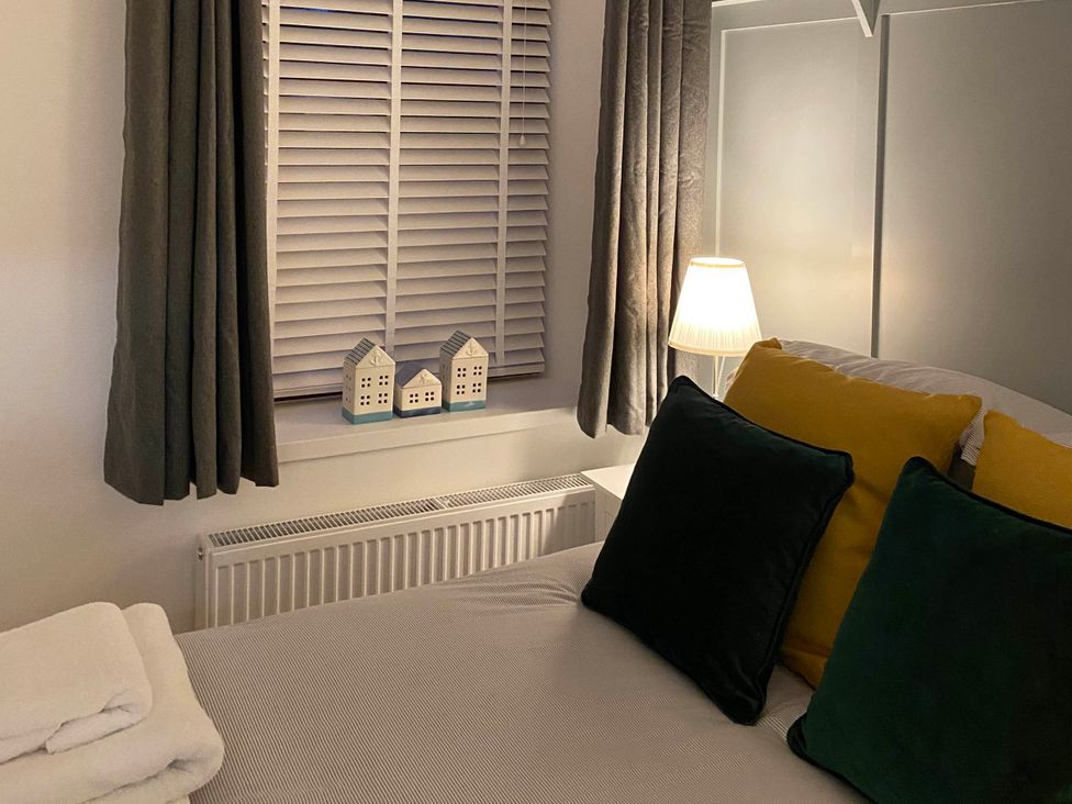 A bedroom with a bed and decorative houses on a window sill at The Old Barn in Manchester