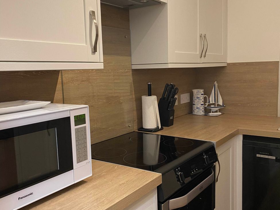 A kitchen with a microwave, oven, and a knife holder at the property in 