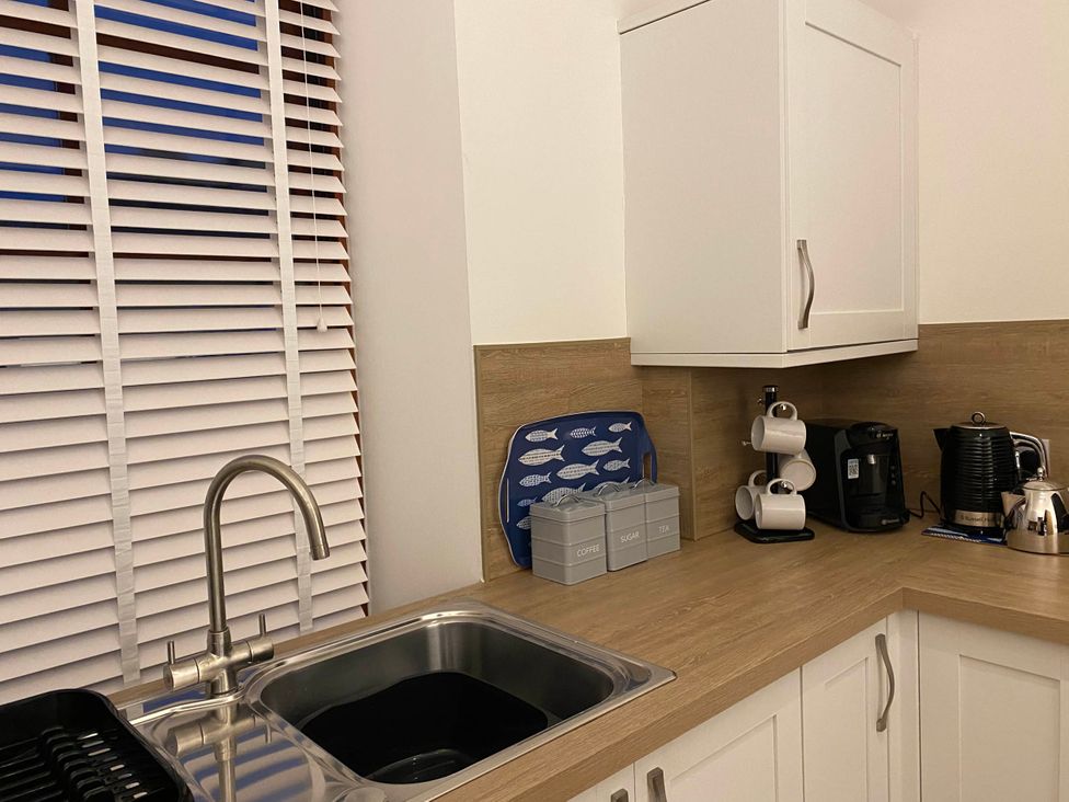 A kitchen featuring a sink and coffee machine with containers at the property location