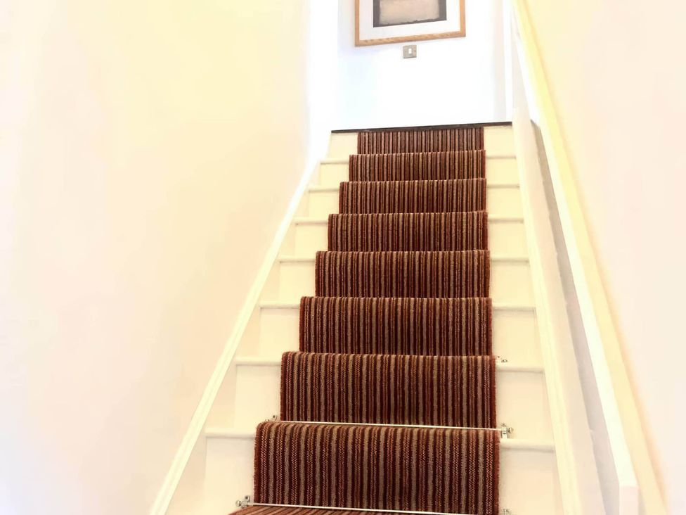 A staircase with carpet runners and a picture on the wall at the property