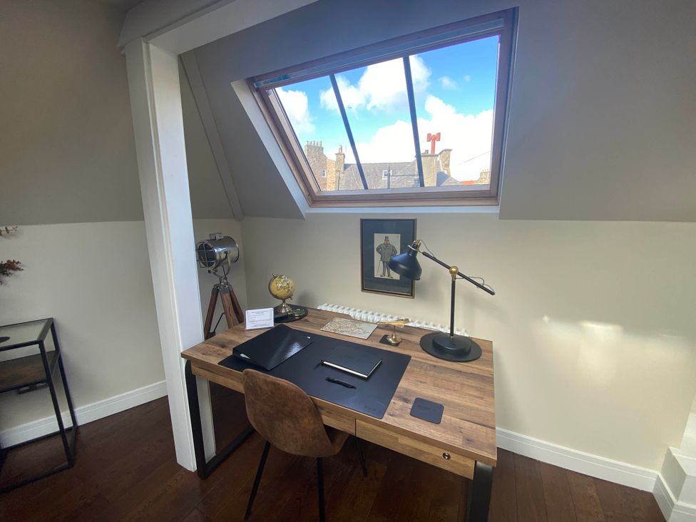 An office with a desk, chair, lamp, and window at the unknown location