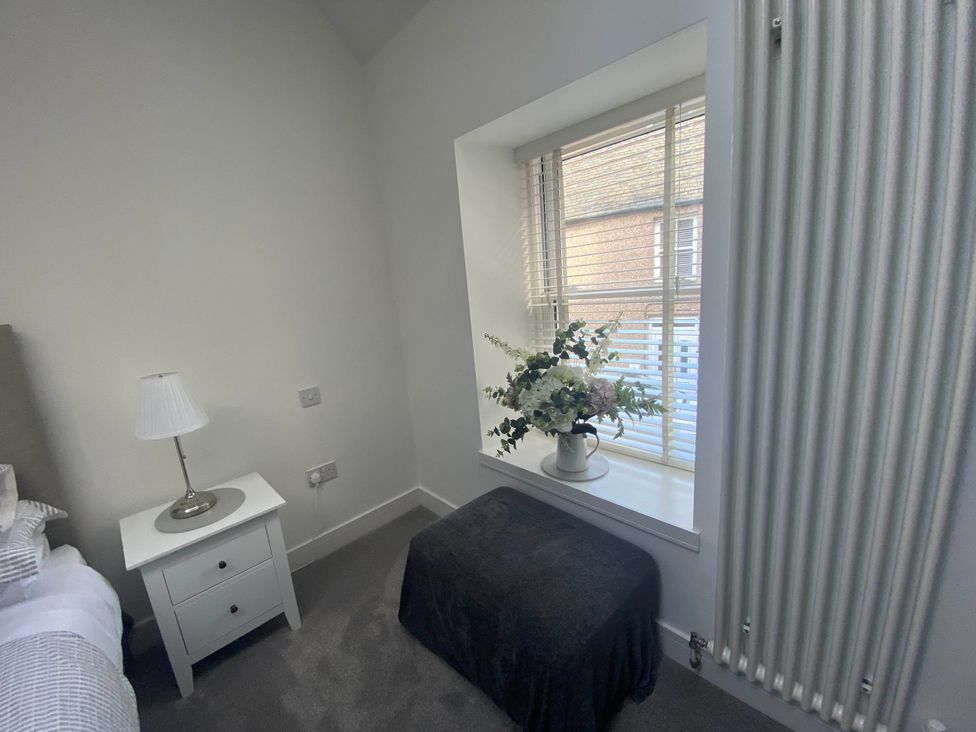 A bedroom with a bed, nightstand, lamp, and window at The Old Barn in Manchester
