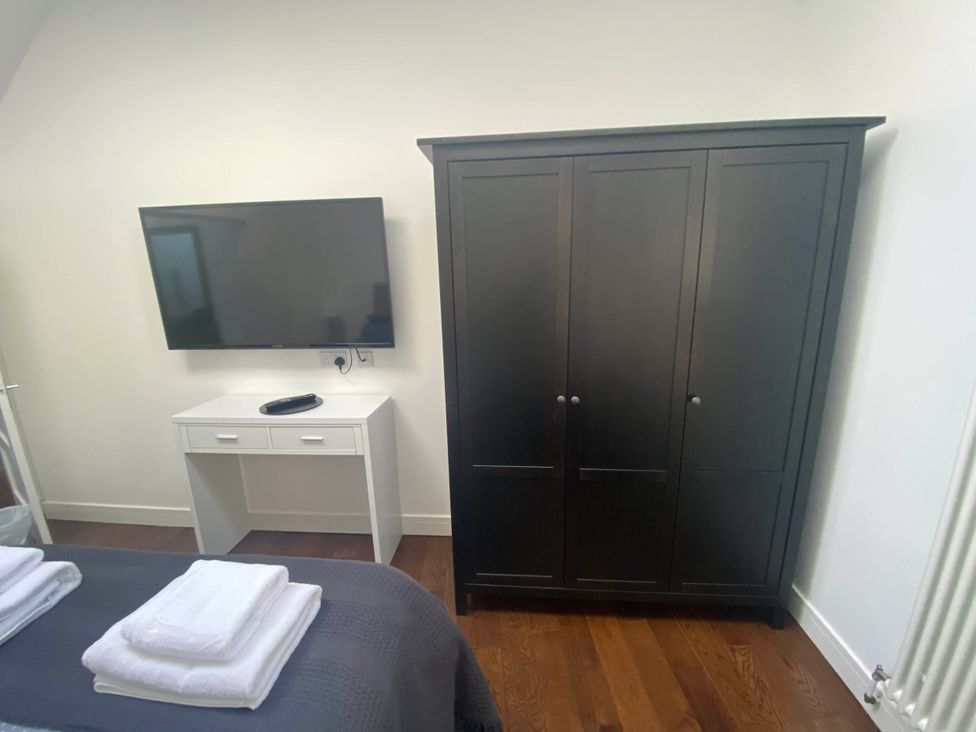 A bedroom with a television and wardrobe at The Old Barn in Manchester