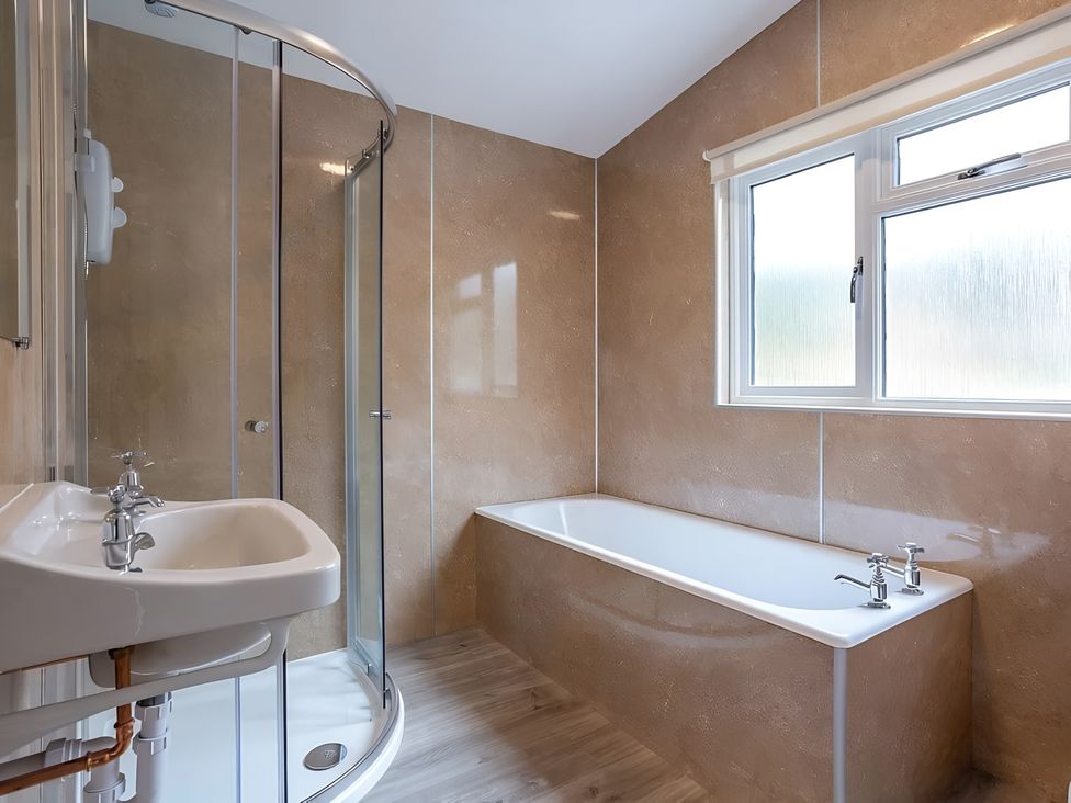A bathroom featuring a shower, bathtub, and sink at Kilninver Chalet