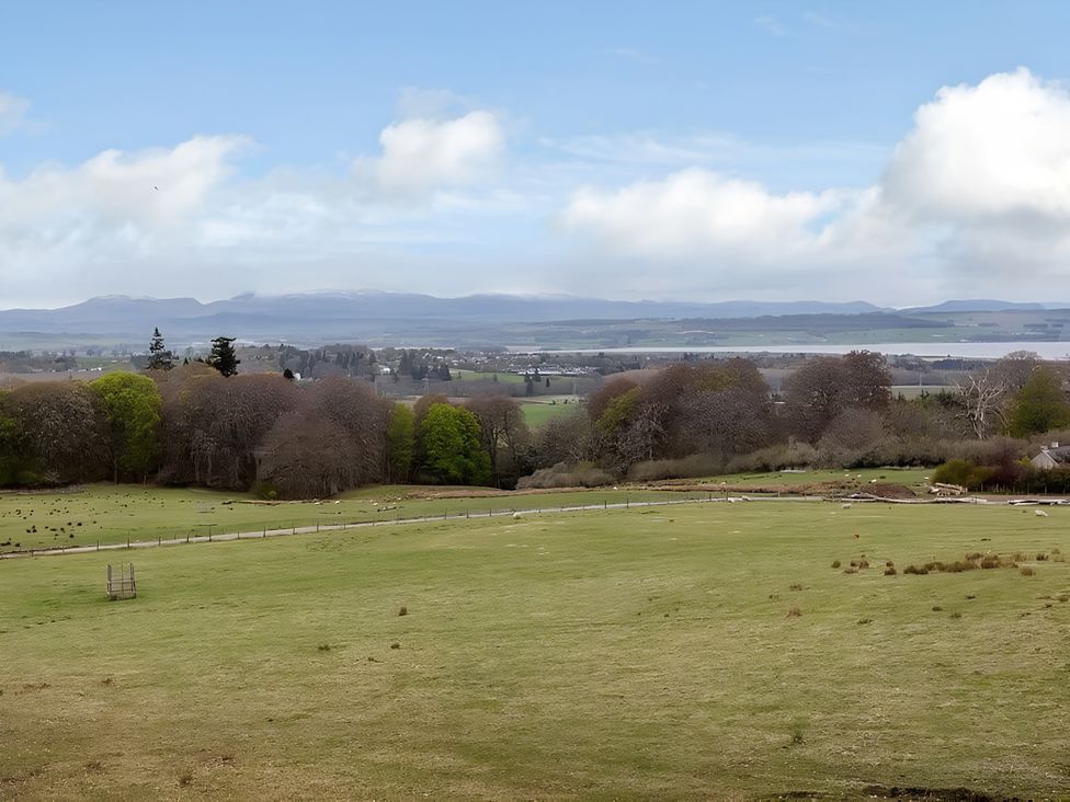 A landscape with grass and trees under a cloudy sky at Kilninver Chalet