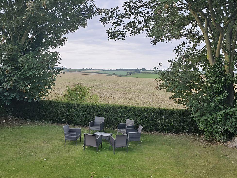 A garden with chairs and a table overlooking a field at Rutland Apartment