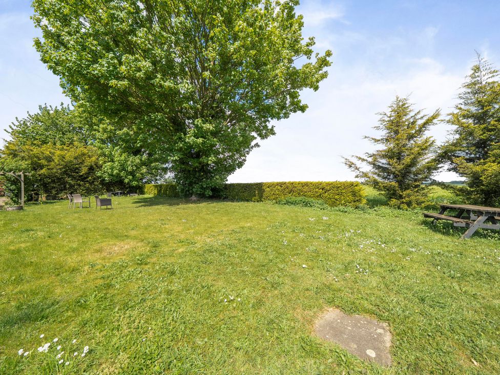 A garden with a large tree and seating at Rutland Apartment in Morcott