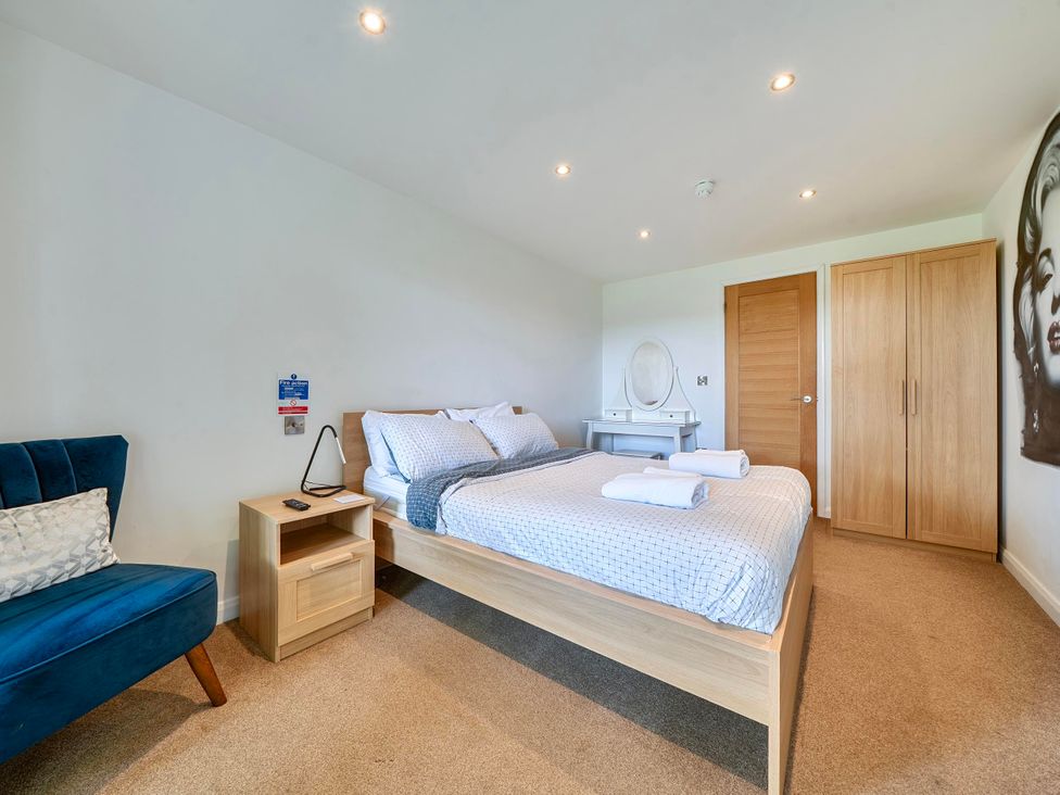 A bedroom with bed, nightstand, chair and wardrobe at Rutland Apartment in Morcott