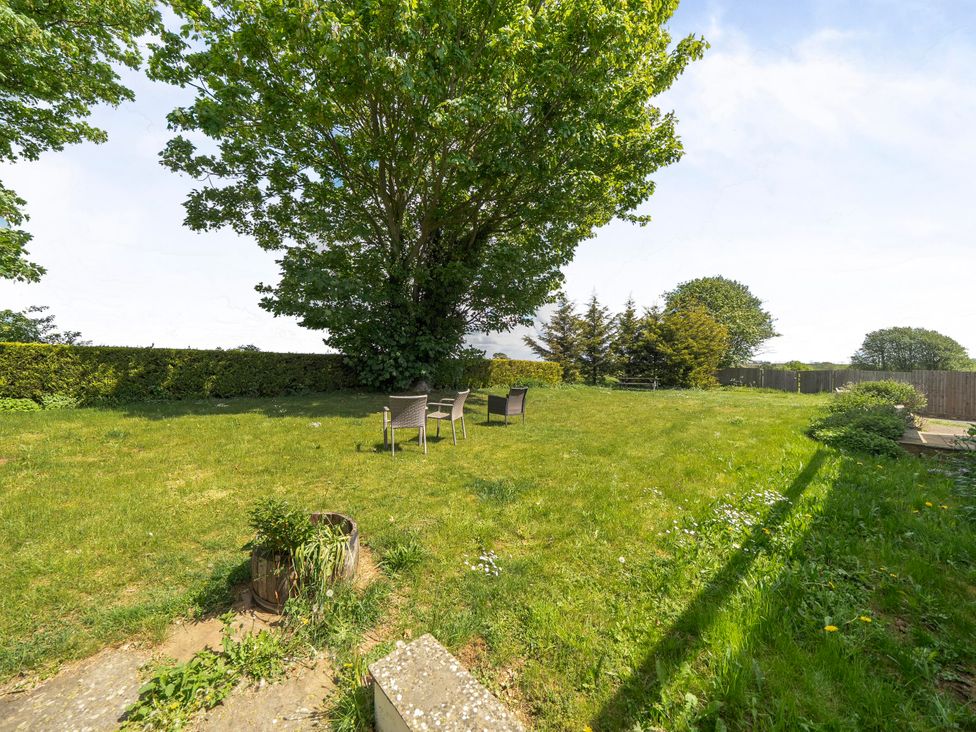 A garden with chairs under a tree at Rutland Apartment in Morcott