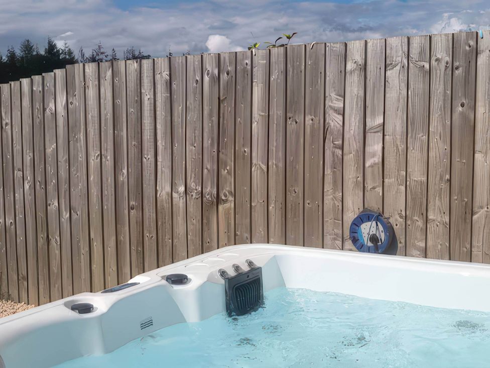 A hot tub with water next to a wooden fence at Old Highwood Barns Dunkeswell
