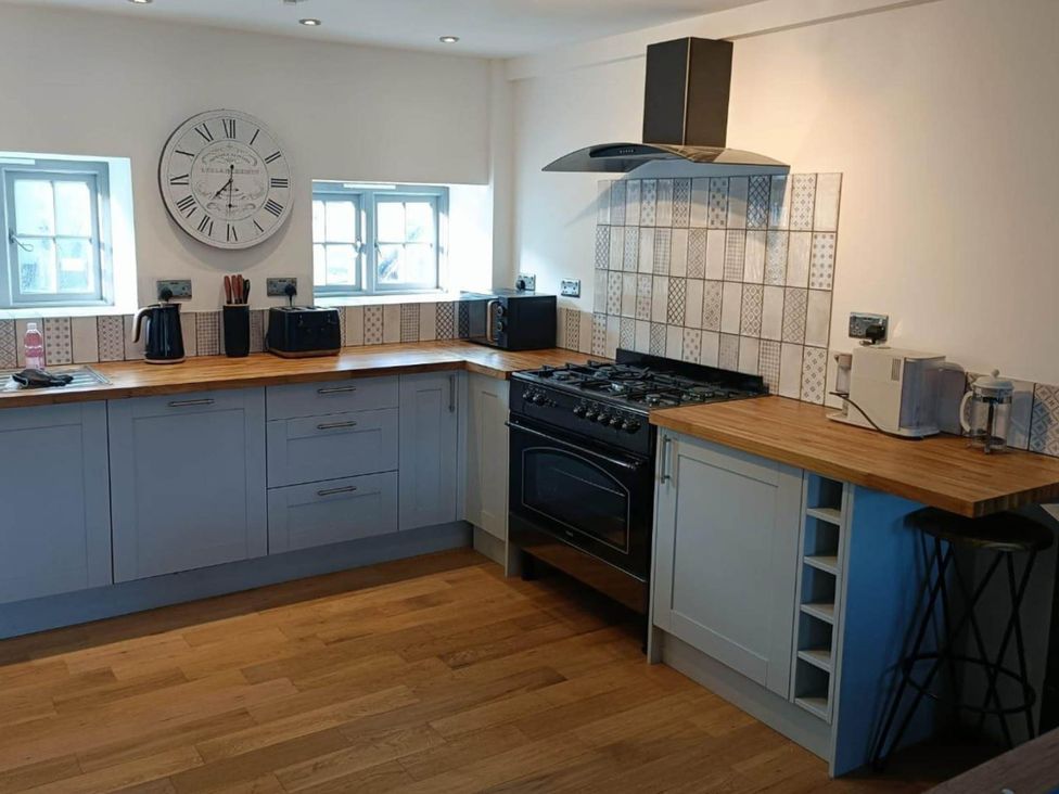 A kitchen with stove, sink, and windows at The Old Highwood Barns in Dunkeswell
