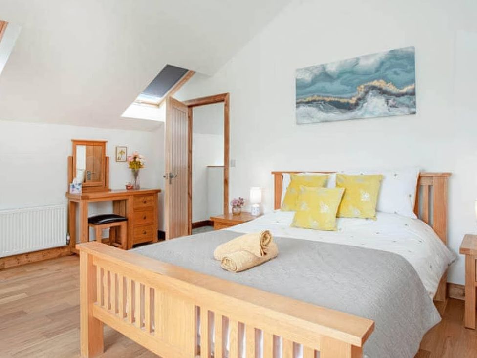 A bedroom with a bed, table, and mirror near a window at The Old Barn in Manchester