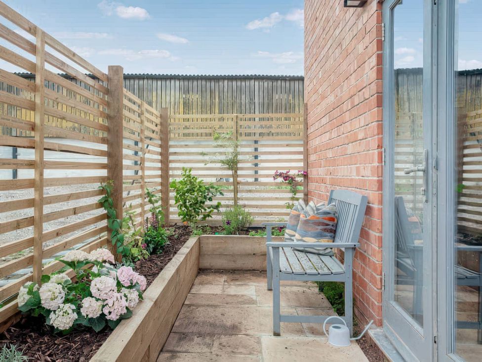 A garden with a bench and flowers in planters at The Old Barn in Manchester