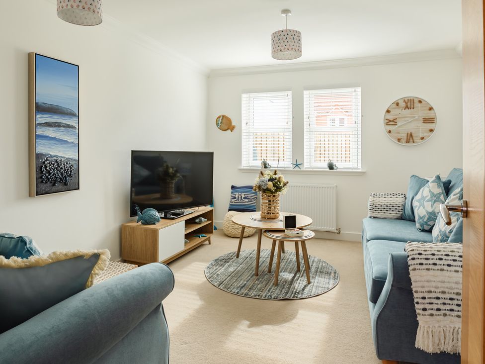 A living room with a sofa and television at Wee Jules By The Sea 