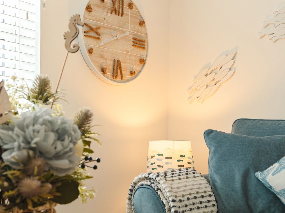 A living room with a clock and lamp at Wee Jules By The Sea
