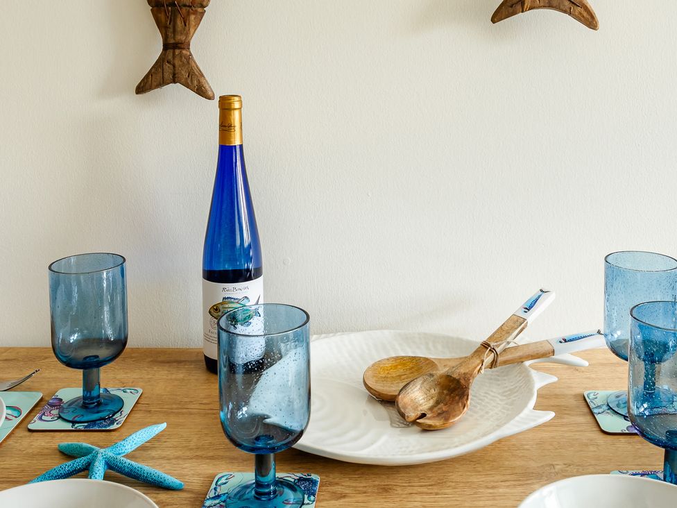 A dining table with a wine bottle and glasses at Wee Jules By The Sea
