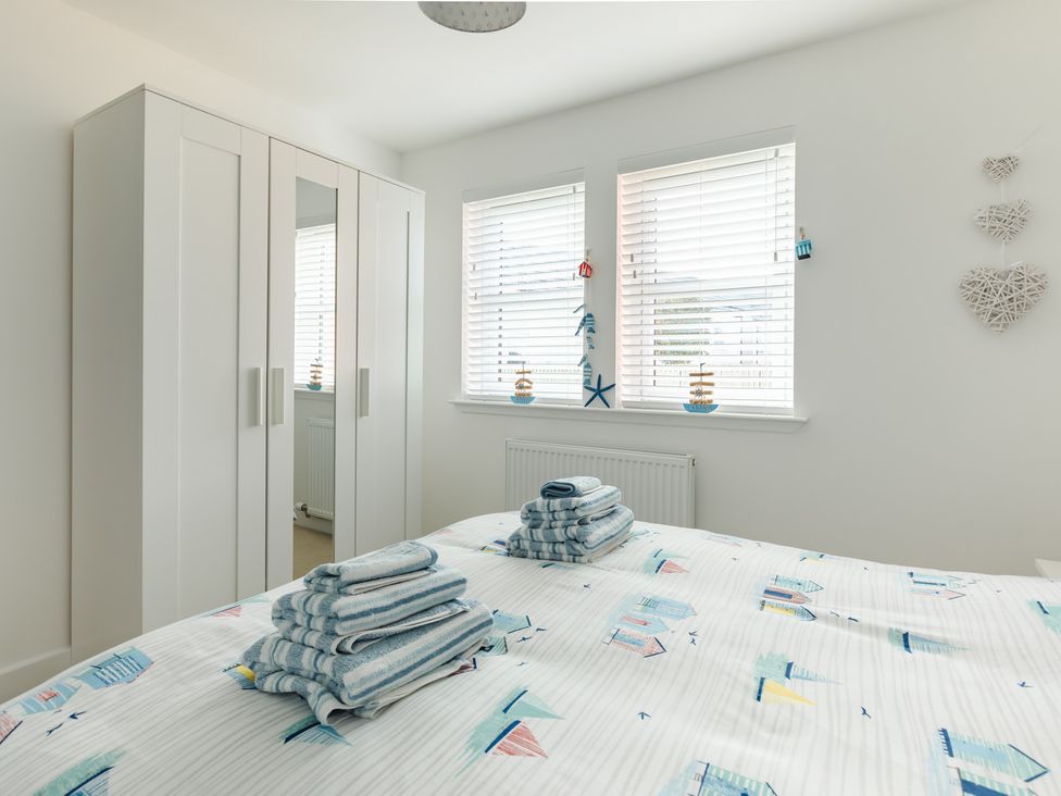 A bedroom with a bed and white wardrobe at Wee Jules By The Sea