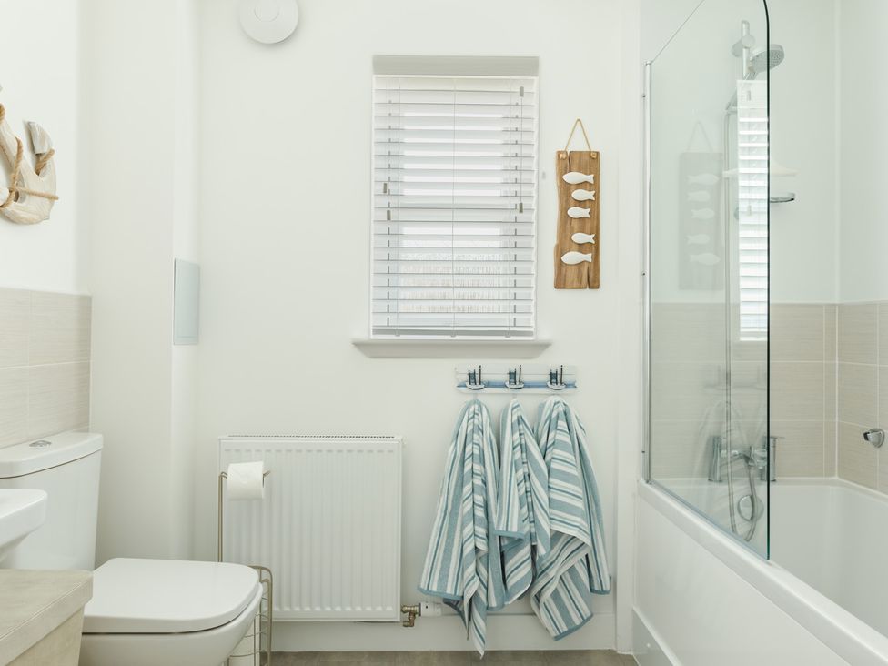 A bathroom with a shower, bathtub, and towels on hooks at Wee Jules By The Sea